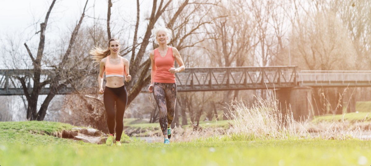 A mother and her grown daughter running together in a park